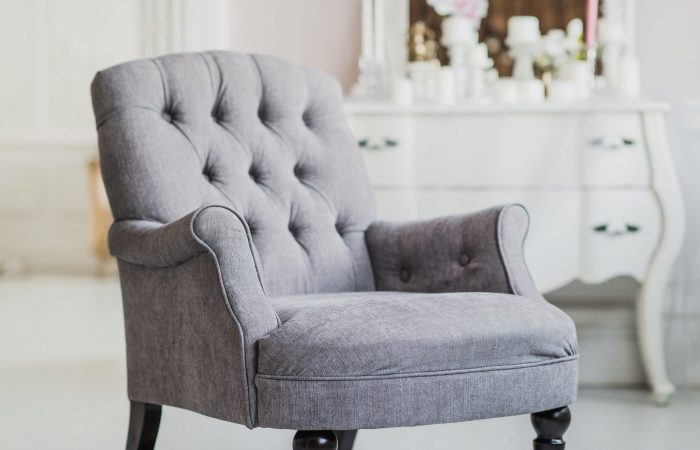 beige color upholstered chair in living room with flowers.