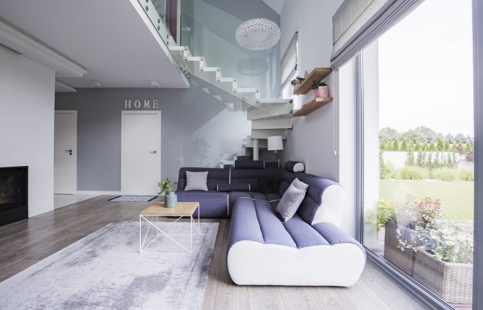 Corner sofa and coffee table under stairs in an elegant living room interior. Real photo