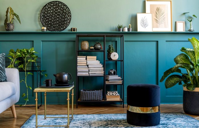 Interior design of living room with gray sofa, design pouf, coffee table, shlef, basket, carpet and elegant personal accessories. Green wood panelling. Modern home decor.